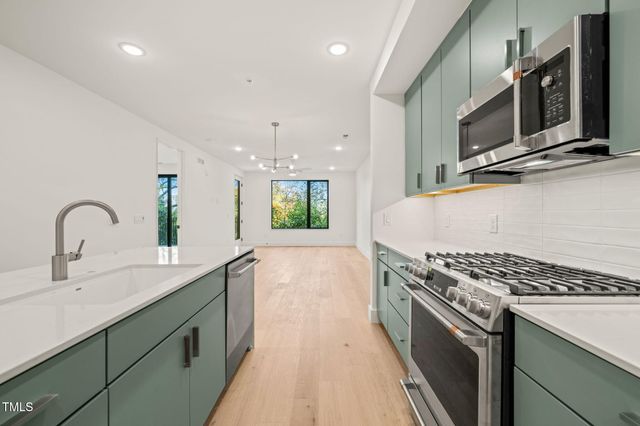 a kitchen with stainless steel appliances kitchen island granite countertop a stove and a sink