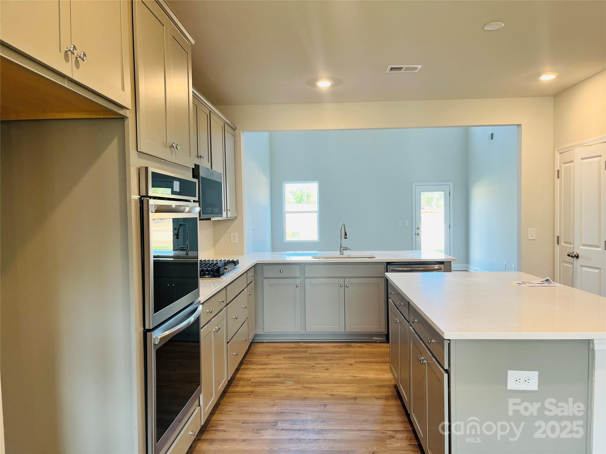 1018 Puddle Pond Road Indian Trail, NC 28079 - Photo 3 of 34 a kitchen with stainless steel appliances granite countertop a sink and dishwasher a stove top oven with wooden floor