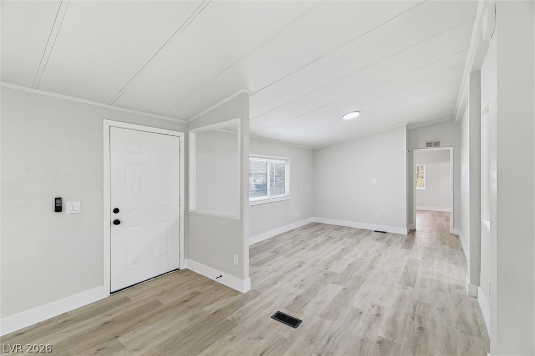 3940 Point Drive Pahrump, NV 89060 - Photo 9 of 35 A well-lit interior space with light wood flooring and a classic white paneled door.