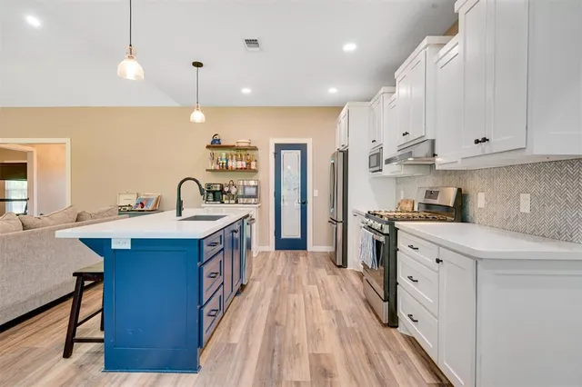 a kitchen with a sink a counter top and a living room view