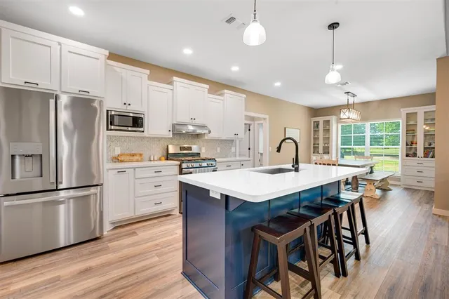 a kitchen with kitchen island granite countertop a sink a counter top space stainless steel appliances and cabinets