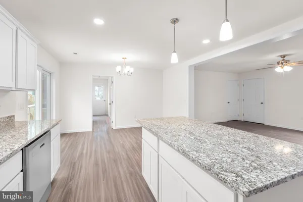a kitchen with stainless steel appliances granite countertop a refrigerator a sink dishwasher a stove and white cabinets with wooden floor