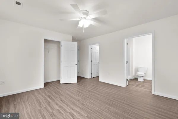 an empty room with wooden floor and a ceiling fan