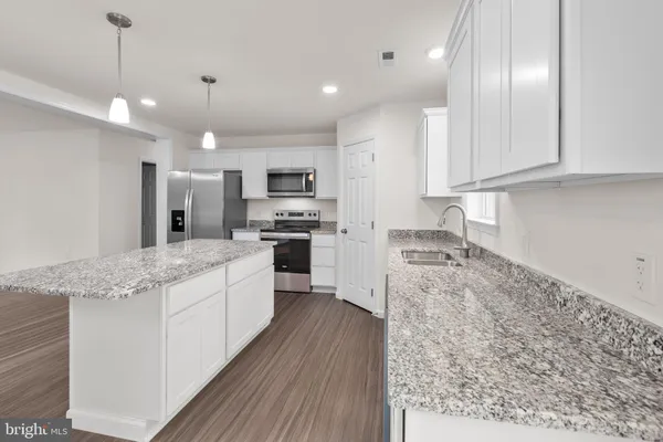 a large kitchen with cabinets wooden floor and stainless steel appliances