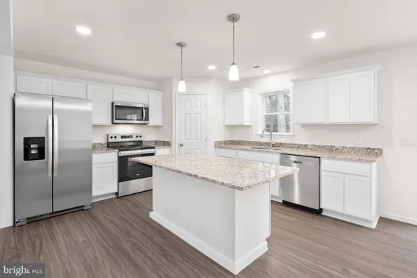 a large kitchen with granite countertop a large counter top appliances and cabinets