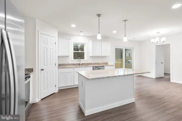 a kitchen with granite countertop stainless steel appliances a refrigerator a sink a stove a microwave and wooden floor