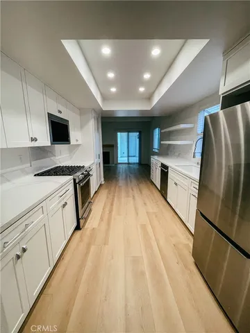 a kitchen with stainless steel appliances a refrigerator a sink and white cabinets
