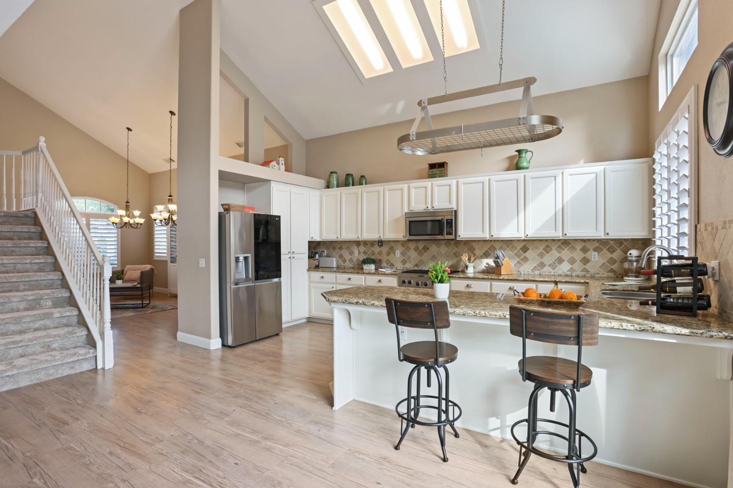 3755 Canyonlands Road Stockton, CA 95209 - Photo 6 of 37 a kitchen with stainless steel appliances a refrigerator a stove a sink dishwasher and white cabinets with wooden floor