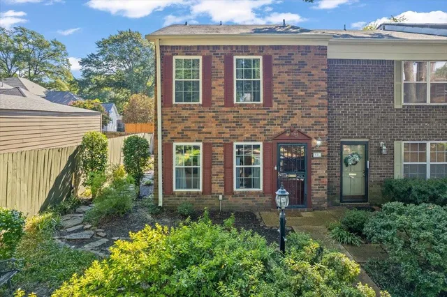 front view of a brick house with a yard and plants