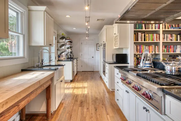 a kitchen with stainless steel appliances granite countertop a sink a stove and a wooden floors
