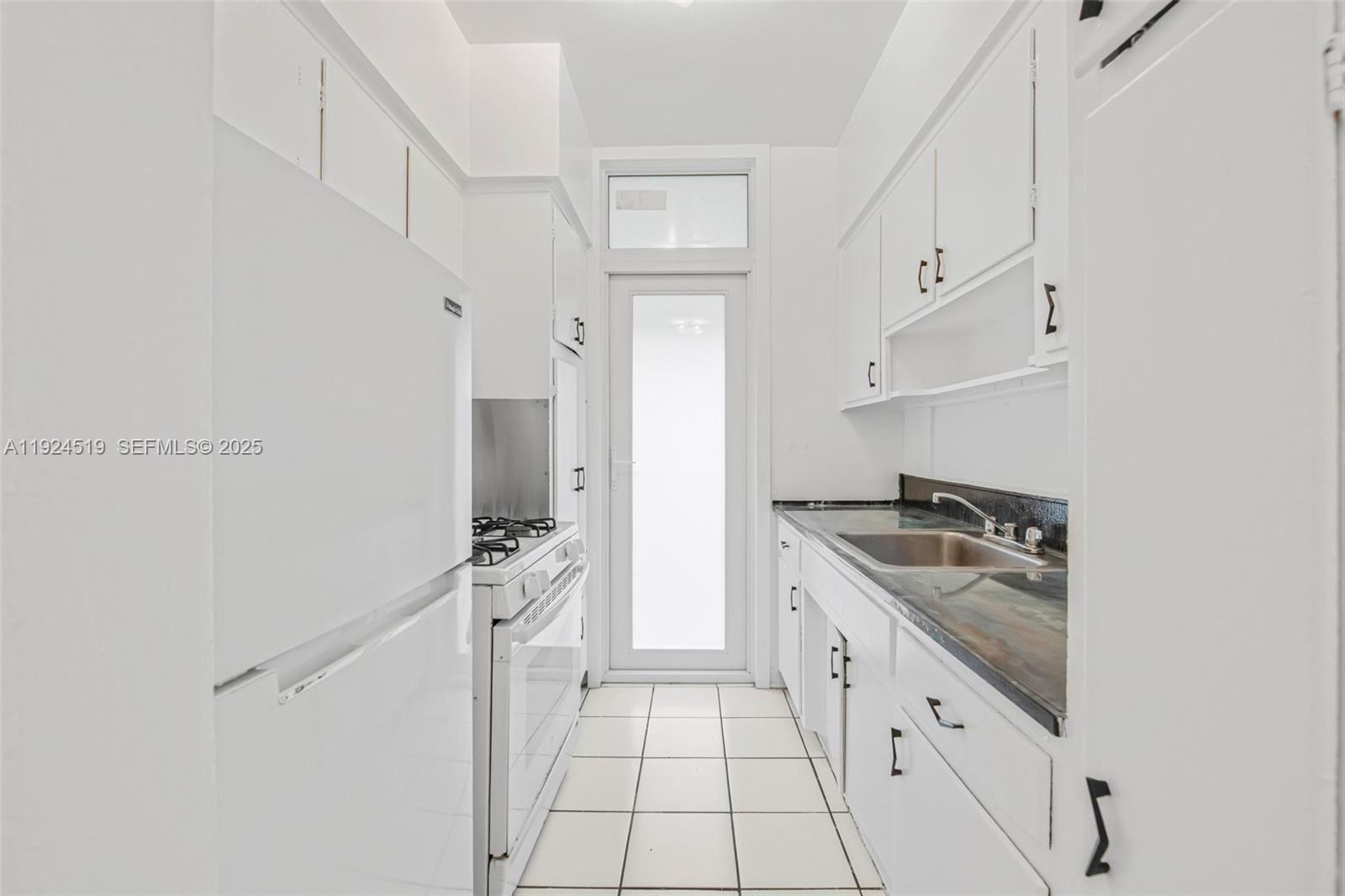 1850 Meridian Avenue, Unit 7 Miami Beach, FL 33139 - Photo 8 of 24 a kitchen with white cabinets and appliances