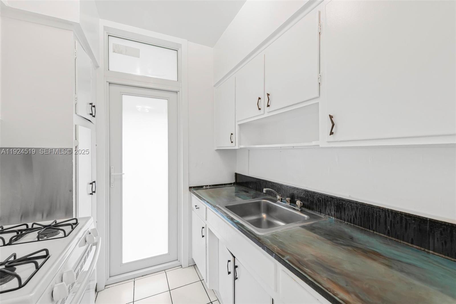 1850 Meridian Avenue, Unit 7 Miami Beach, FL 33139 - Photo 9 of 24 a kitchen with granite countertop a sink and a stove