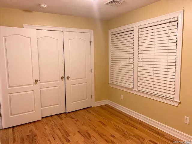 a view of an empty room with a window and hardwood floor