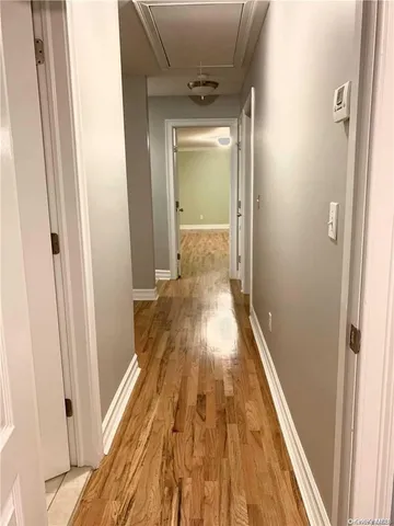 a view of a hallway with wooden floor and a bathroom