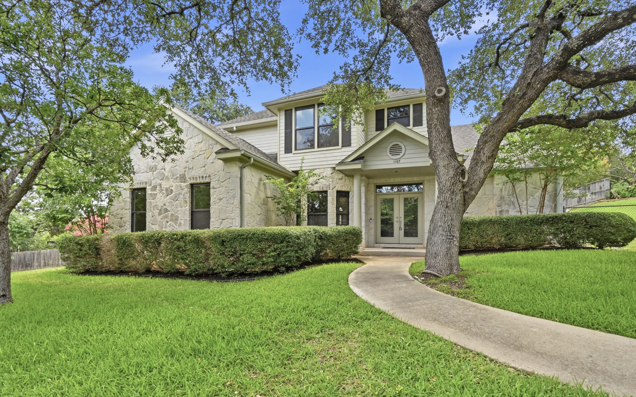 1107 Bowie Road Austin, TX 78733 - Photo 2 of 40 A graceful stone and siding exterior welcomes you, framed by mature trees and manicured landscaping.