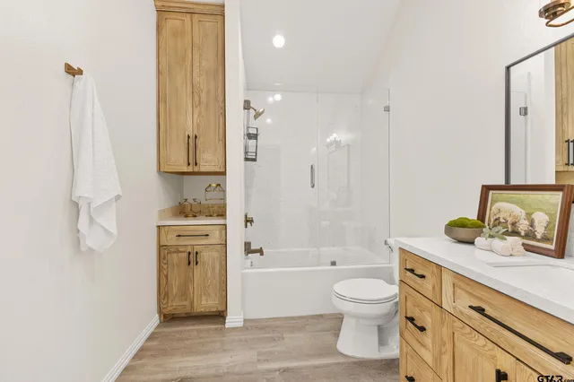 a bathroom with a granite countertop sink a toilet and shower