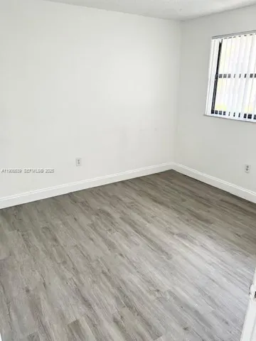 an empty room with wooden floor and window
