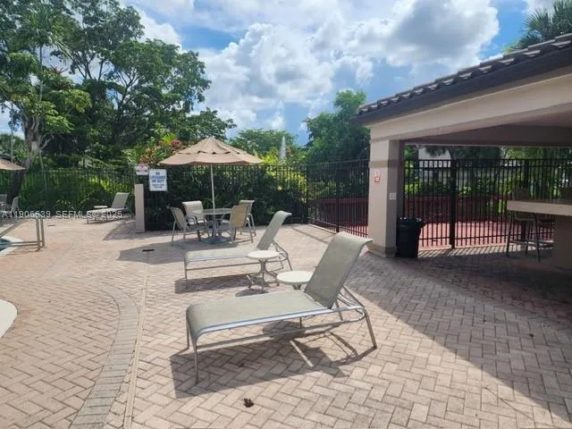 a view of a patio with a dining table and chairs under an umbrella with large trees