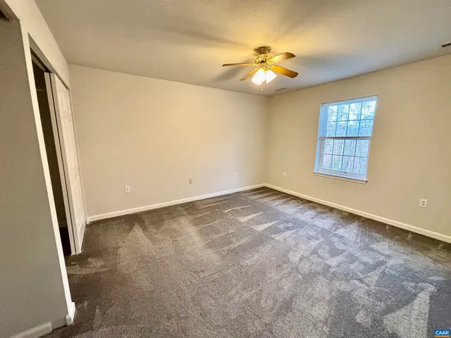 an empty room with windows and chandelier fan
