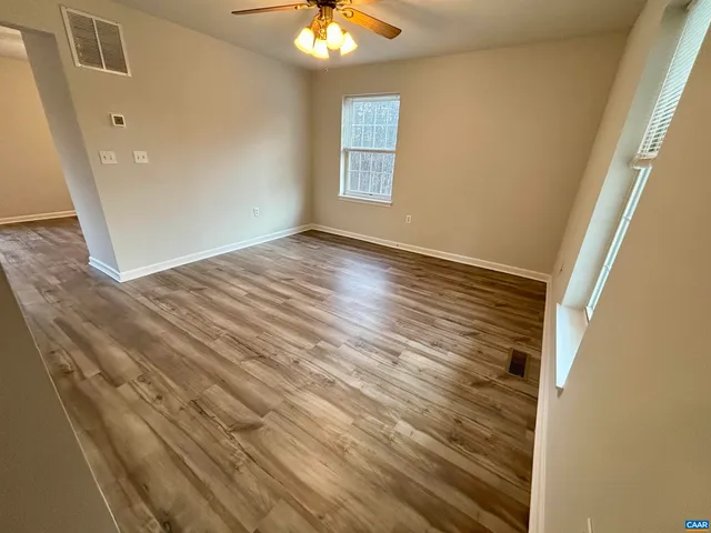 en empty room with wooden floor and fan