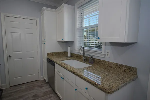 a kitchen with a granite countertop sink and cabinets