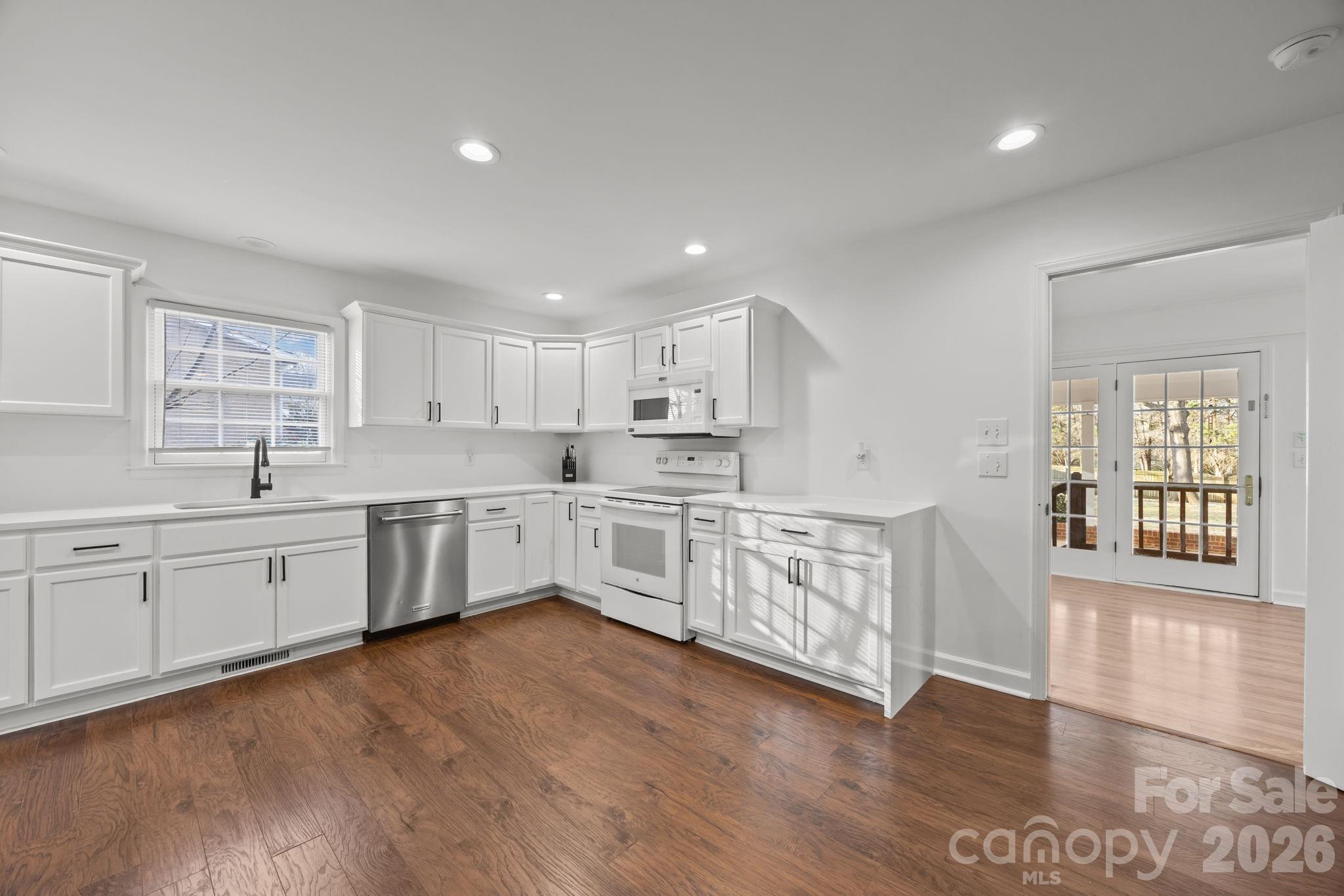 2431 Fox Hollow Road Mint Hill, NC 28227 - Photo 7 of 30 a large white kitchen with cabinets a sink a window and wooden floor