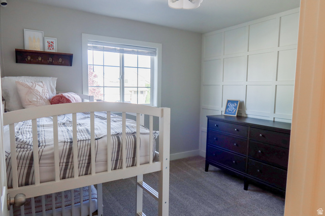 1204 North 3020th Street West Provo, UT 84601 - Photo 34 of 35 Bedroom 2 featuring a large multi-pane window, carpet flooring, and a decorative grid-paneled accent wall