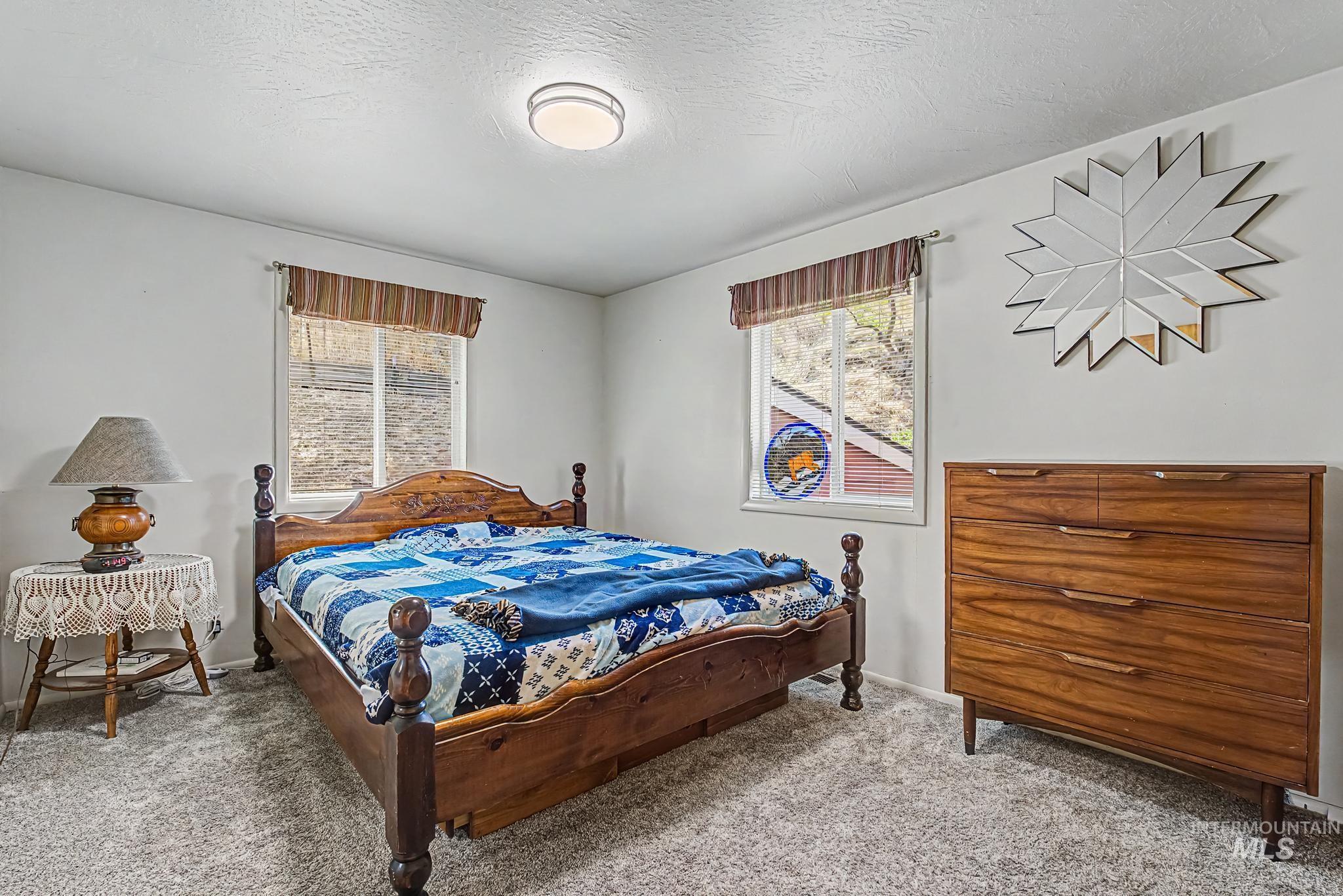 4311 Frozen Dog Road Emmett, ID 83617 - Photo 21 of 31 Bedroom featuring soft gray carpet, two windows with striped valances, and a ceiling-mounted flush light fixture
