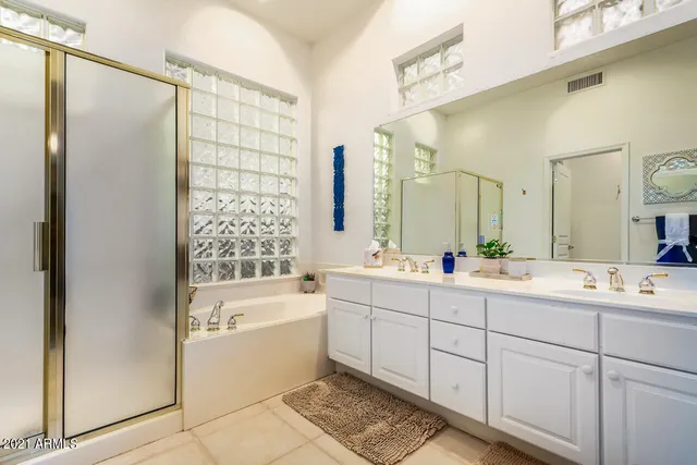 a bathroom with a double vanity sink mirror and bathtub
