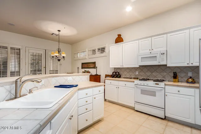 a kitchen with granite countertop white cabinets white stainless steel appliances with a sink and dishwasher