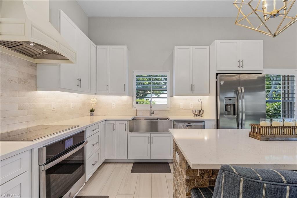7596 San Miguel Way Naples, FL 34109 - Photo 11 of 34 a kitchen with stainless steel appliances a sink a stove a refrigerator cabinets and dining table