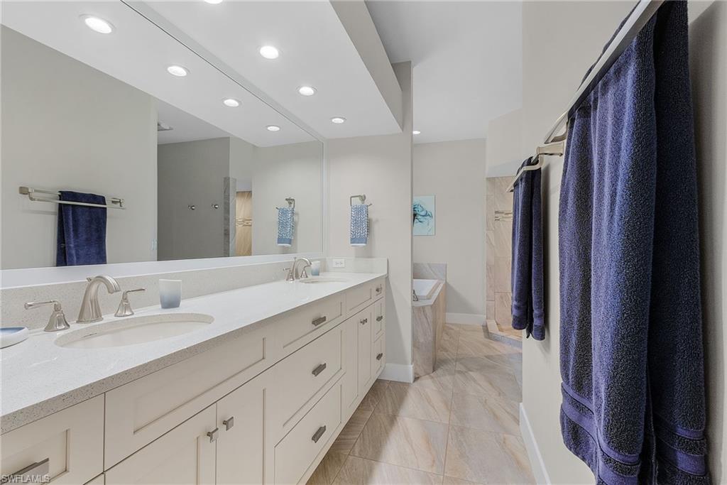 7596 San Miguel Way Naples, FL 34109 - Photo 15 of 34 a spacious bathroom with a double vanity sink and a mirror
