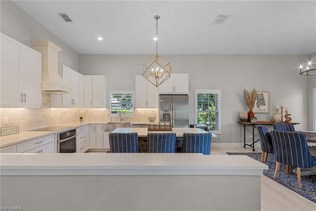 7596 San Miguel Way Naples, FL 34109 - Photo 8 of 34 a open kitchen with kitchen island a stove a table and chairs