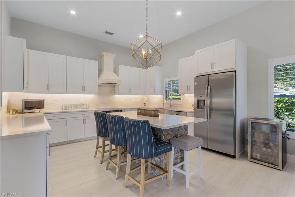 7596 San Miguel Way Naples, FL 34109 - Photo 10 of 34 a kitchen with stainless steel appliances a table chairs refrigerator and cabinets