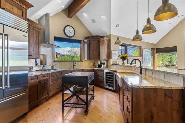 a kitchen with stainless steel appliances granite countertop a sink a stove and a dining table with wooden floor