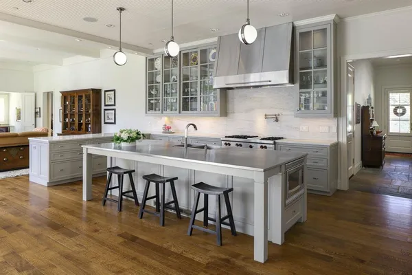 a kitchen with stainless steel appliances granite countertop a sink a stove and a wooden floors