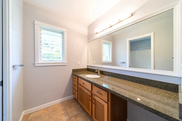 a bathroom with a granite countertop sink and a window