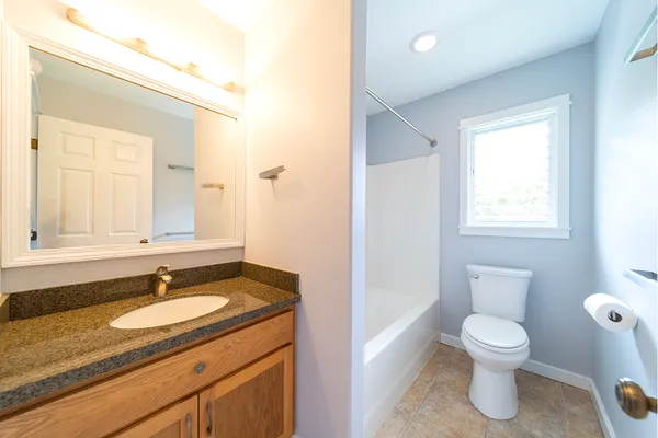 a bathroom with a granite countertop sink a toilet and a mirror