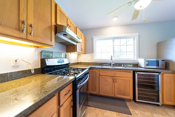 a kitchen with stainless steel appliances granite countertop a sink a stove and a wooden cabinets