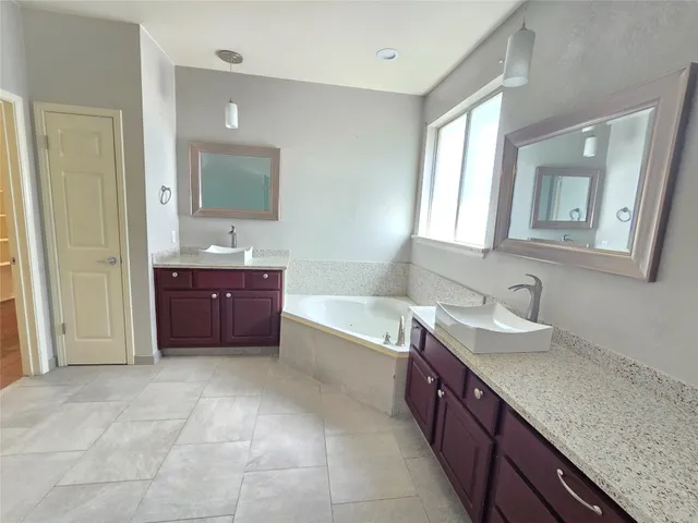 a spacious bathroom with a granite countertop double vanity sink a mirror and a bathtub