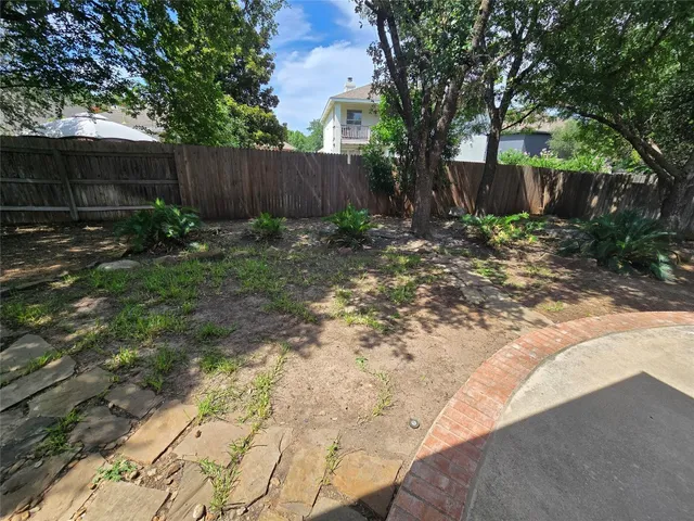 a view of backyard with potted plants and large tree