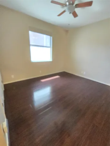 an empty room with a ceiling fan and windows