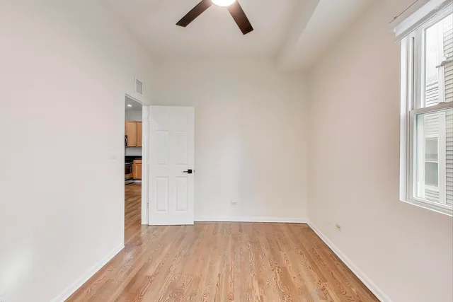 an empty room with ceiling fan and window