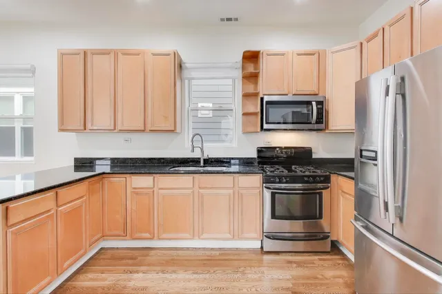 a kitchen with stainless steel appliances granite countertop a stove a sink and a microwave