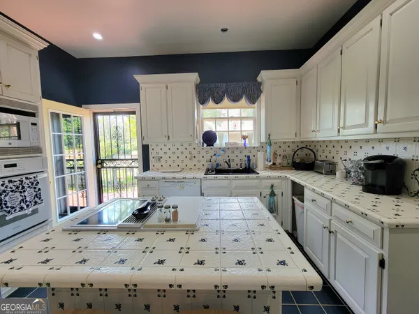 a kitchen with stainless steel appliances kitchen island granite countertop a sink a stove a refrigerator and cabinets