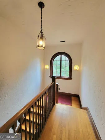 a view of a hallway with wooden floor and a chandelier