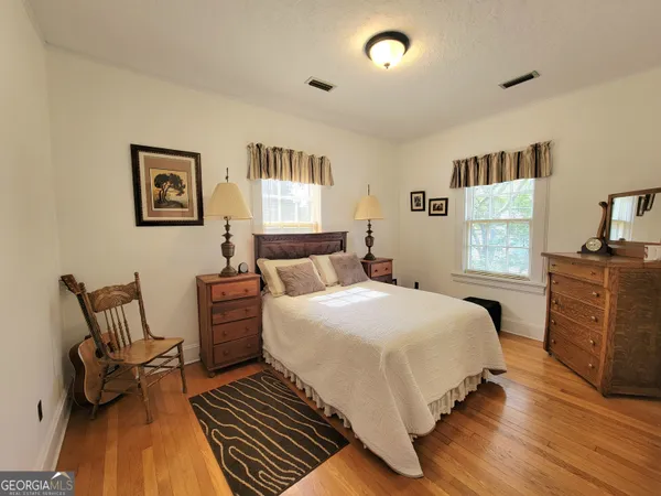 a bedroom with a bed mirror on dresser and a chandelier