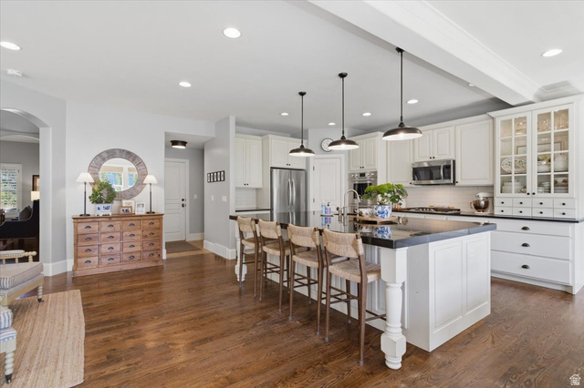 1257 Rigby Road Kaysville, UT 84037 - Photo 16 of 55 Gourmet kitchen featuring a large central island with seating, white shaker cabinetry, stainless steel appliances, and dark countertops