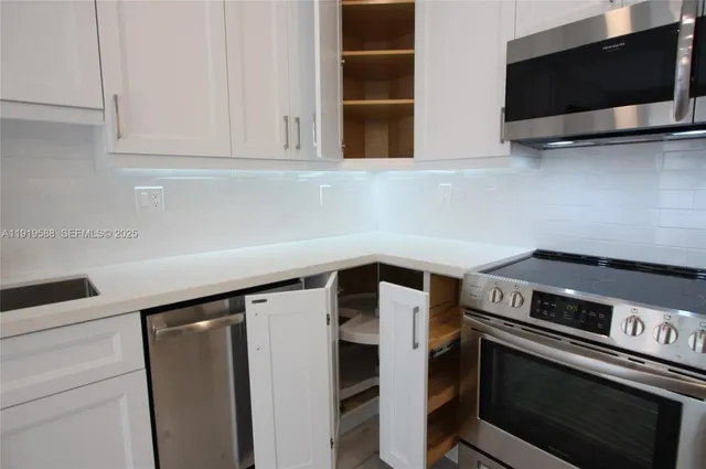 a kitchen with stainless steel appliances a stove a microwave and a white cabinets