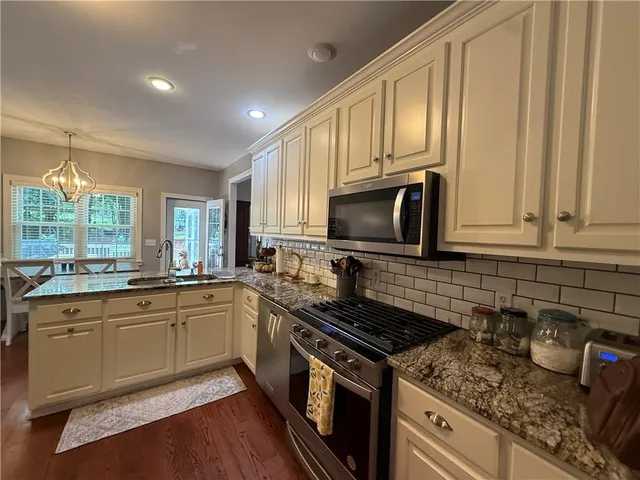 a kitchen with granite countertop a sink stove and cabinets